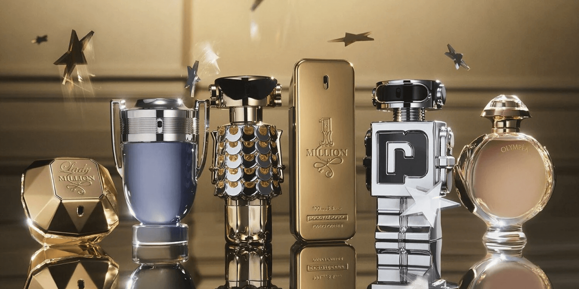 Collection of various perfume bottles on a reflective surface with a gold background